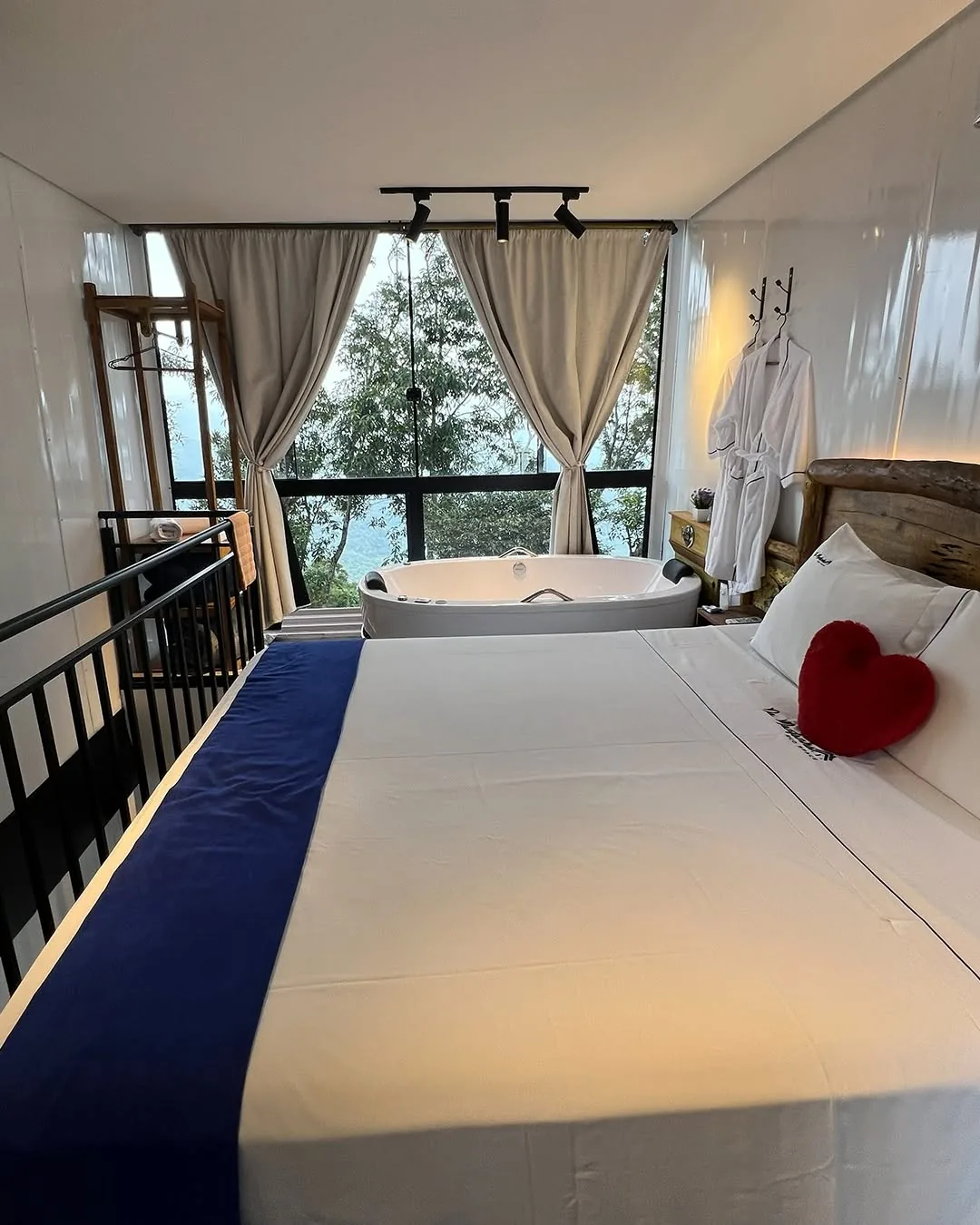 Quarto com cama de casal e janela para a mata