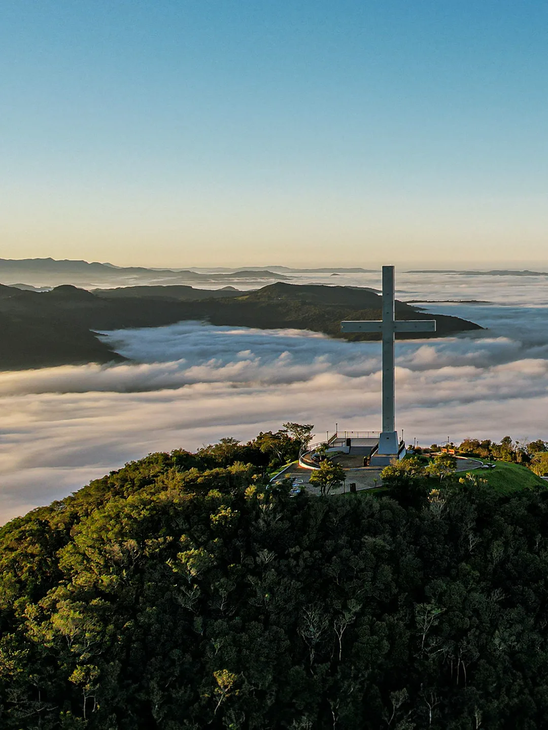 Cruzeiro no alto do morro, acima de um mar de nuvens